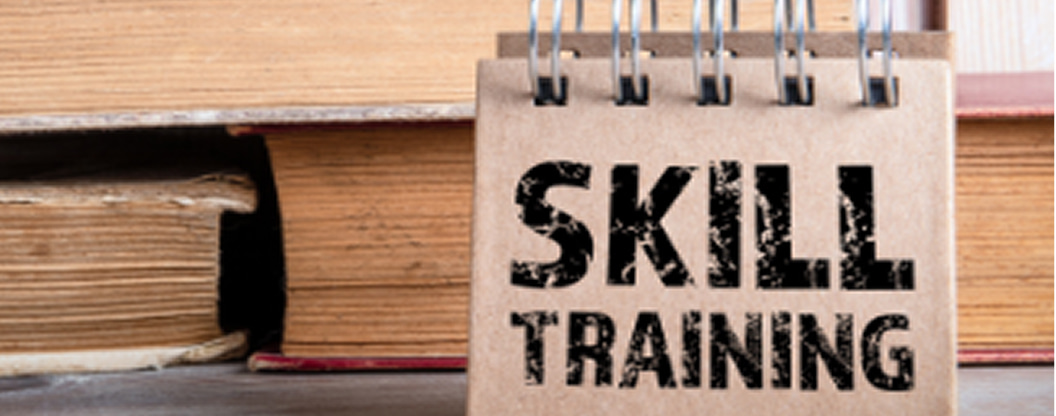 古い本が積み重なった前に置かれた「SKILL TRAINING」という文字が印字されたリングノート。知識の蓄積と専門スキルの習得を象徴しており、学習や研修フェーズであることを明確に伝える画像です。