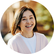 屋外の明るい日差しの中で、満面の笑みを浮かべる日本人女性（熟年層）